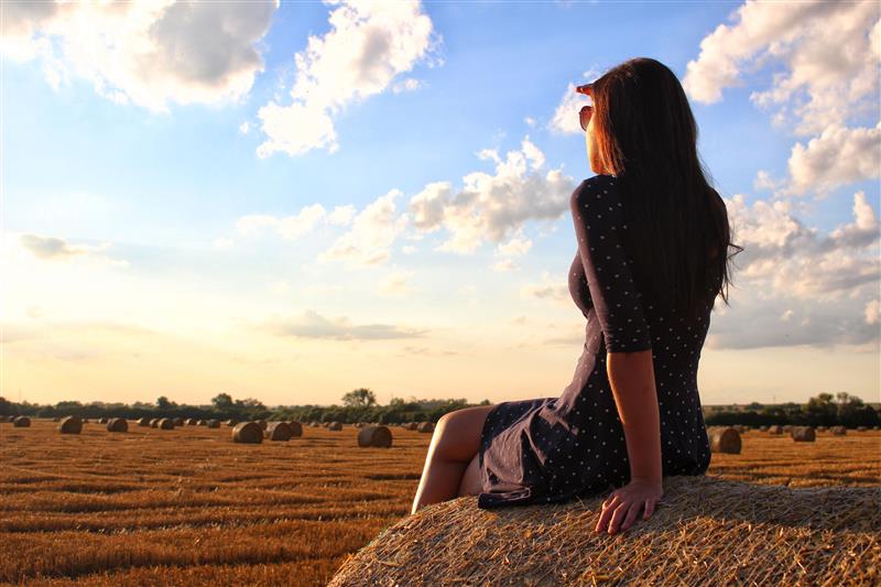 Woman sitting on haystack and watching the sunset #2
