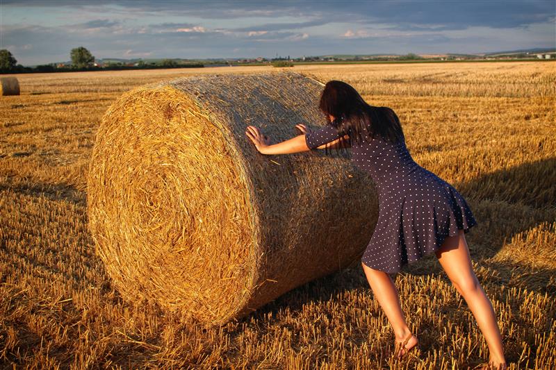 Woman pushing the haystack at sunset