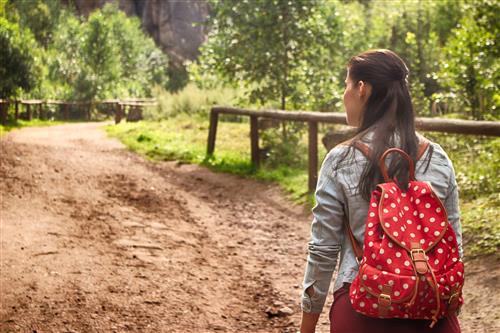Woman on dirt road with a red backpack