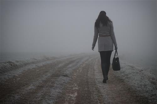 Woman walking a dirt road in fog
